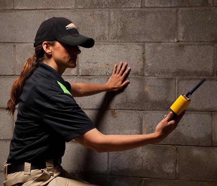 A SERVPRO technician is shown testing for moisture in a basement